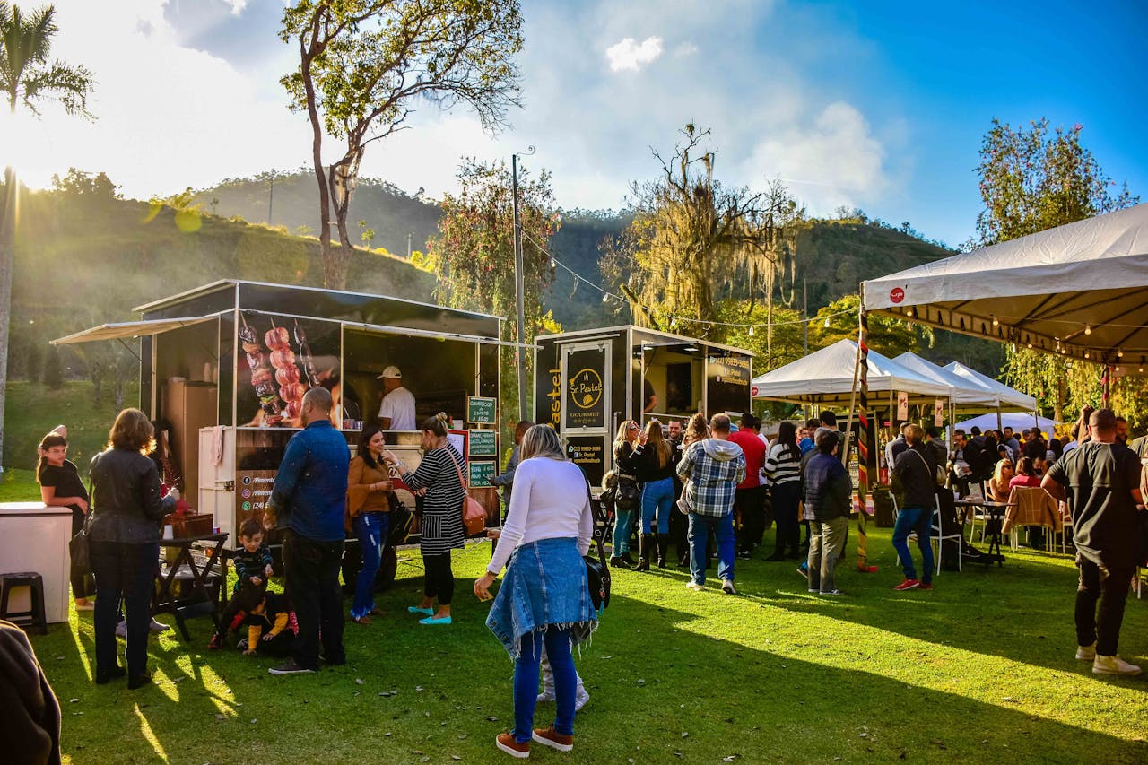 People attend a food truck festival in a park