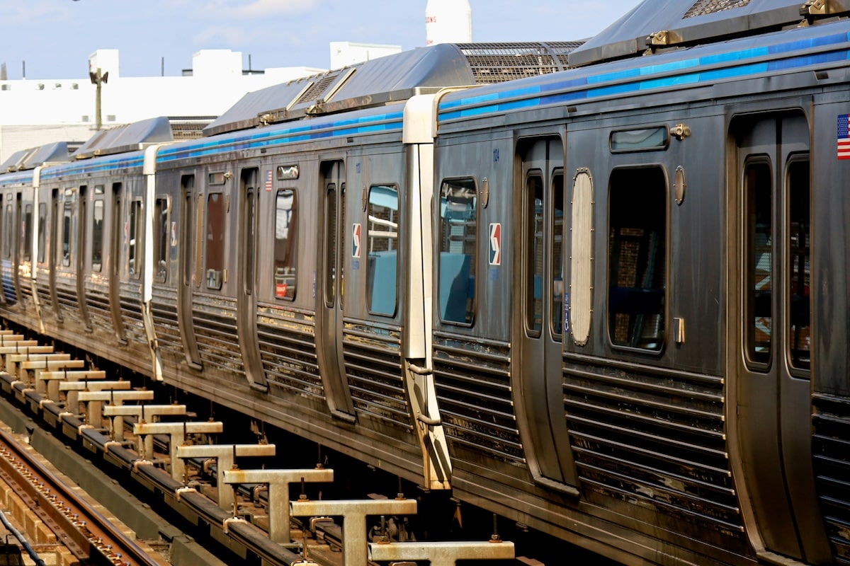 A close-up view of a metallic subway train with SEPTA logos on the cars, stopped on an elevated railway track in an urban setting.