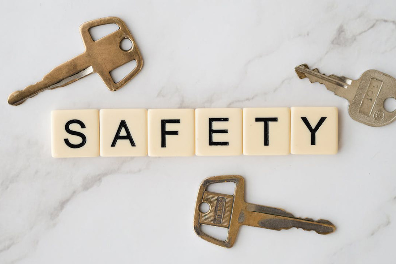 Scrabble blocks spell out the word safety against a marble surface surrounded by three keys>